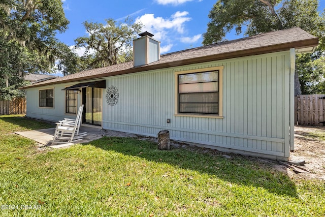 rear view of property featuring a patio and a lawn