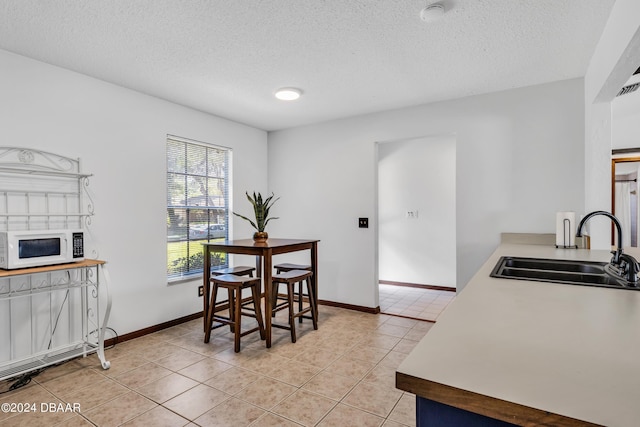 dining area featuring sink, a textured ceiling, and light tile patterned floors