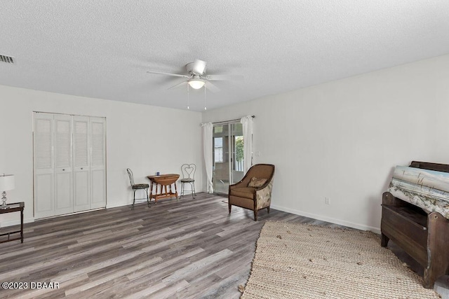 sitting room with ceiling fan, hardwood / wood-style flooring, and a textured ceiling