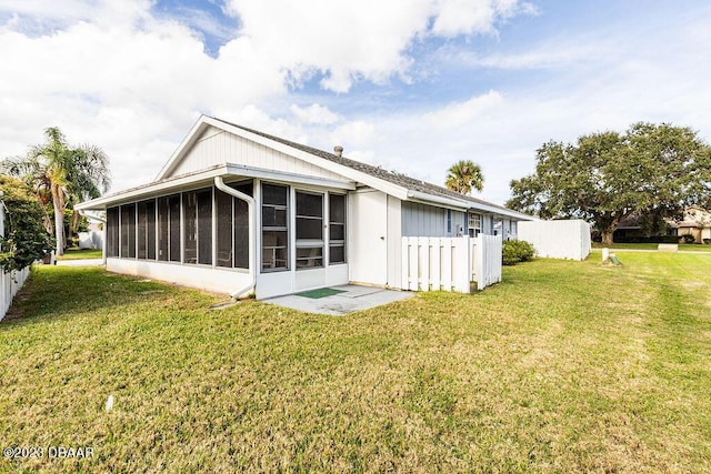 rear view of property featuring a sunroom and a lawn