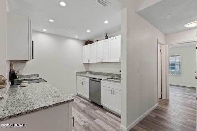 kitchen with sink, light stone counters, light wood-type flooring, stainless steel dishwasher, and white cabinets