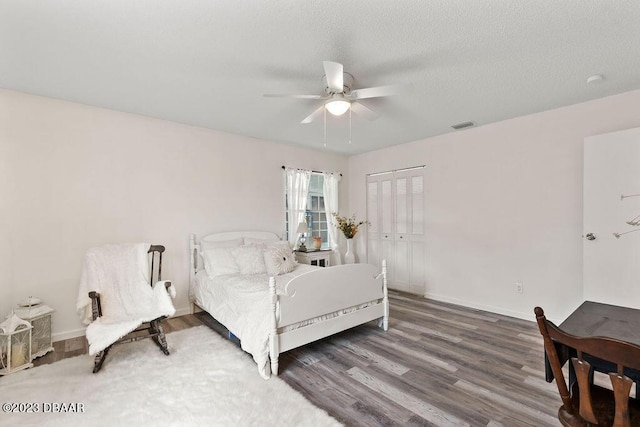 bedroom featuring a textured ceiling, dark wood-type flooring, a closet, and ceiling fan