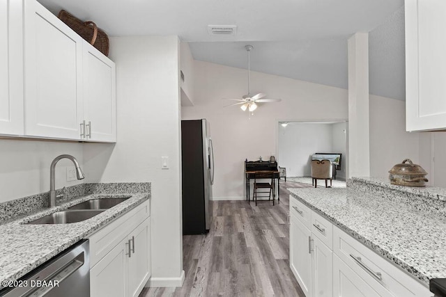 kitchen featuring lofted ceiling, sink, stainless steel appliances, light stone countertops, and white cabinets