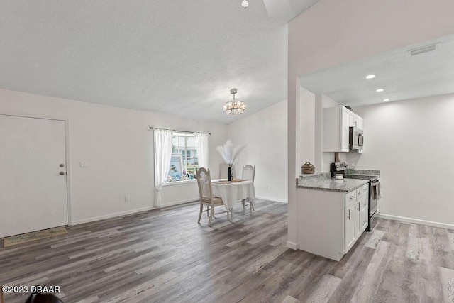 kitchen with white cabinetry, stainless steel appliances, light stone counters, and hardwood / wood-style flooring