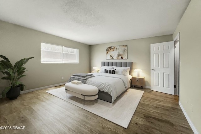 bedroom featuring a textured ceiling, baseboards, and wood finished floors