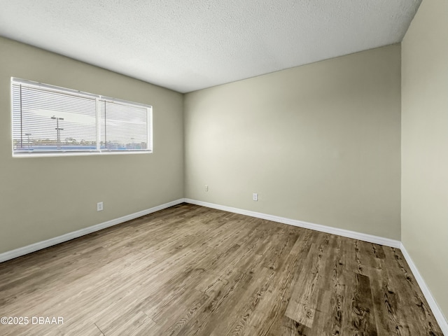 empty room featuring baseboards, a textured ceiling, and wood finished floors