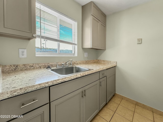 kitchen with light tile patterned flooring, gray cabinets, light countertops, and a sink