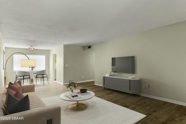 living room featuring baseboards, wood finished floors, visible vents, and a textured ceiling