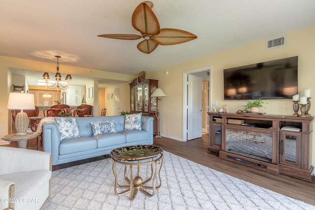 living room with wood-type flooring, a textured ceiling, and ceiling fan with notable chandelier