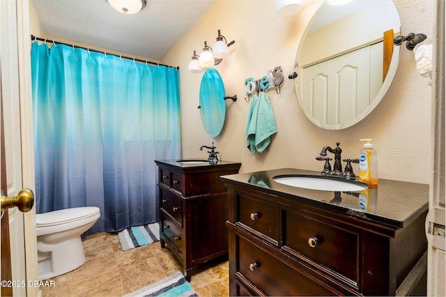 bathroom with curtained shower, two vanities, toilet, and a sink
