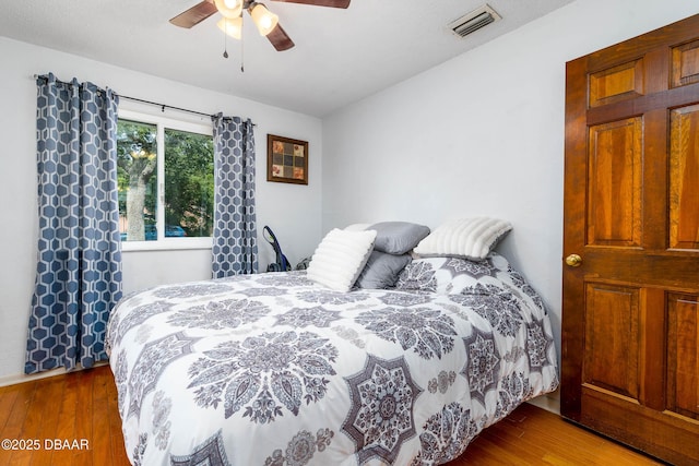 bedroom with visible vents, wood finished floors, and a ceiling fan