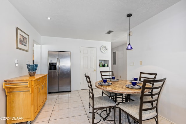 dining room featuring electric panel, a textured ceiling, and light tile patterned floors