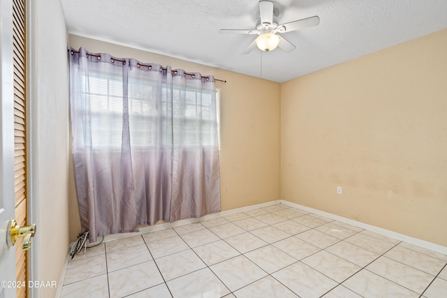 unfurnished room with light tile patterned flooring, ceiling fan, and a textured ceiling