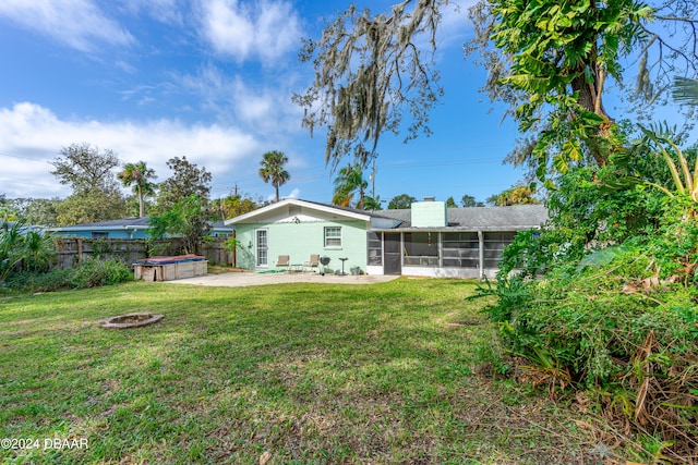 back of property featuring a patio, a sunroom, a lawn, and an outdoor fire pit