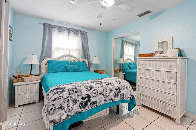 tiled bedroom featuring a textured ceiling, ceiling fan, and a closet