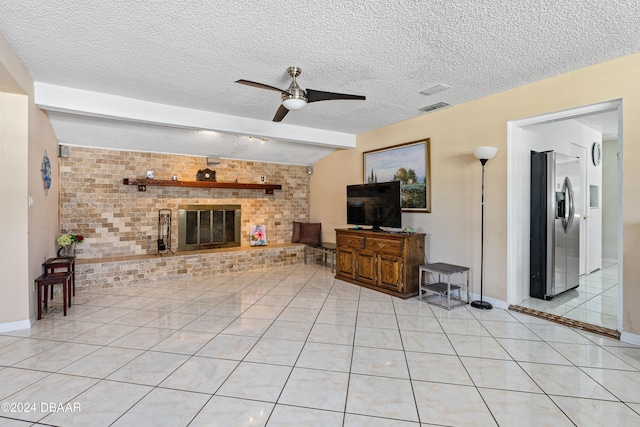 living room with a textured ceiling, light tile patterned floors, a brick fireplace, ceiling fan, and brick wall