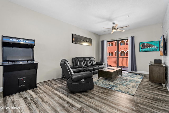 living area featuring wood finished floors, a ceiling fan, and baseboards
