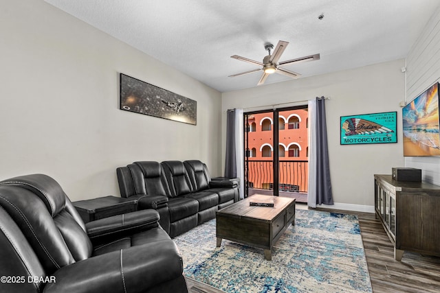 living area with dark wood-style floors, baseboards, a ceiling fan, and a textured ceiling