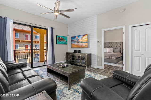 living area featuring wood finished floors, a ceiling fan, and baseboards