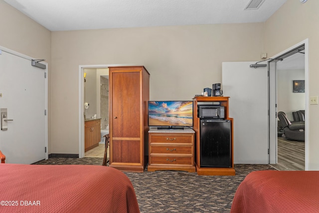 bedroom with refrigerator, visible vents, and carpet