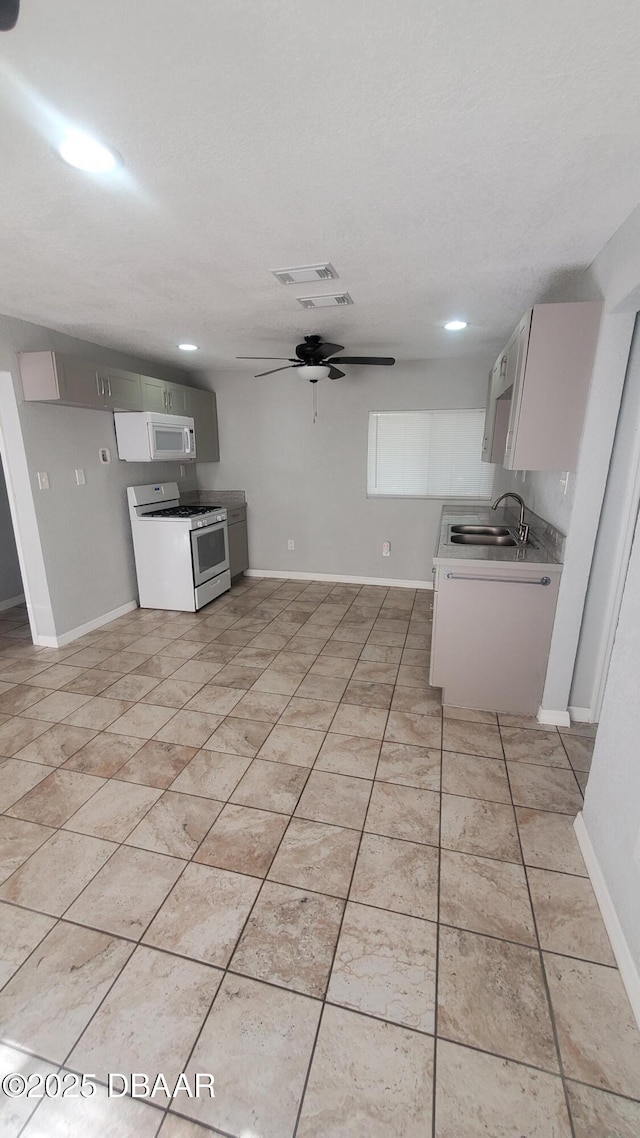 kitchen with white appliances, light tile patterned floors, a ceiling fan, and a sink