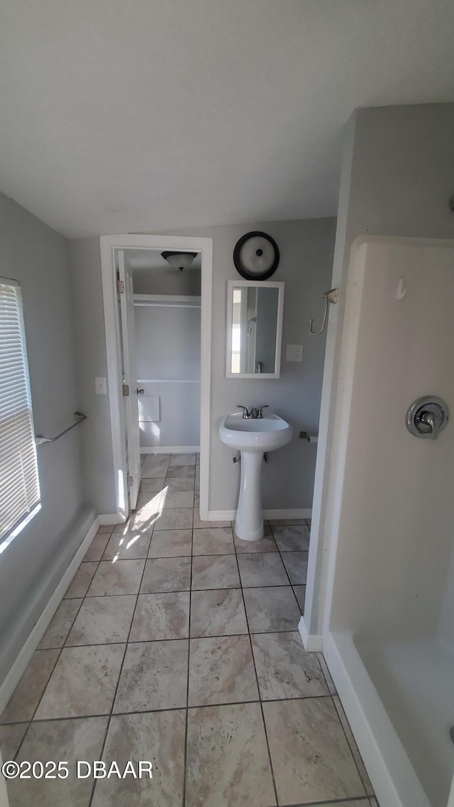 bathroom featuring tile patterned floors, a shower, and baseboards