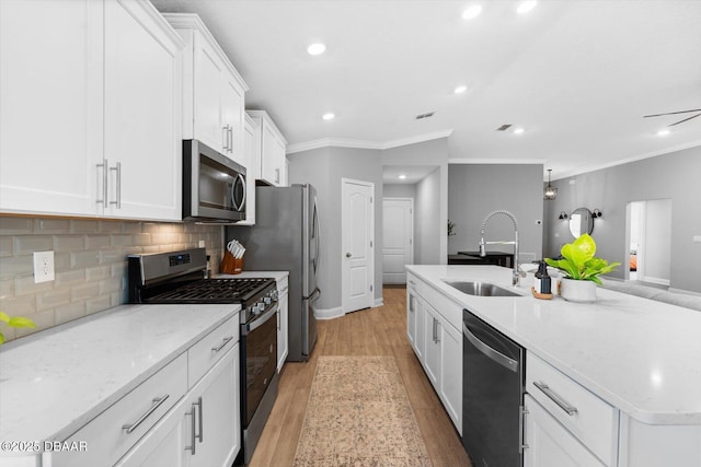 kitchen featuring appliances with stainless steel finishes, crown molding, sink, a center island with sink, and white cabinetry