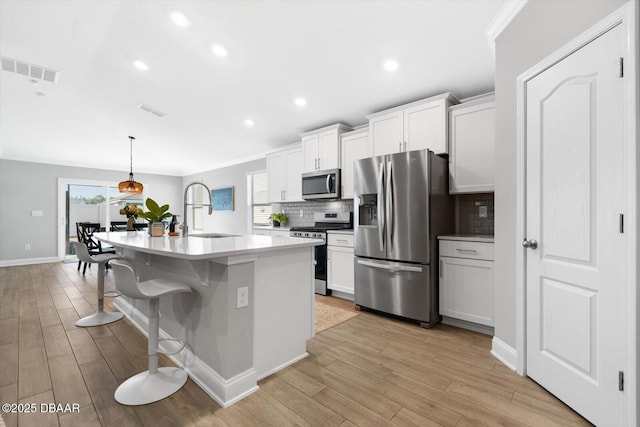 kitchen with a center island with sink, sink, white cabinetry, and stainless steel appliances