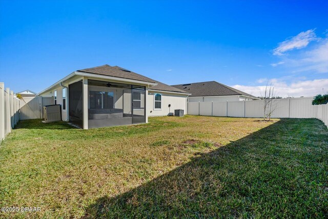 back of house featuring a sunroom, a yard, and central AC