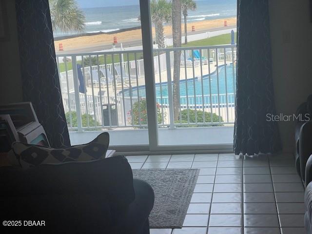 tiled living room featuring a view of the beach and a water view