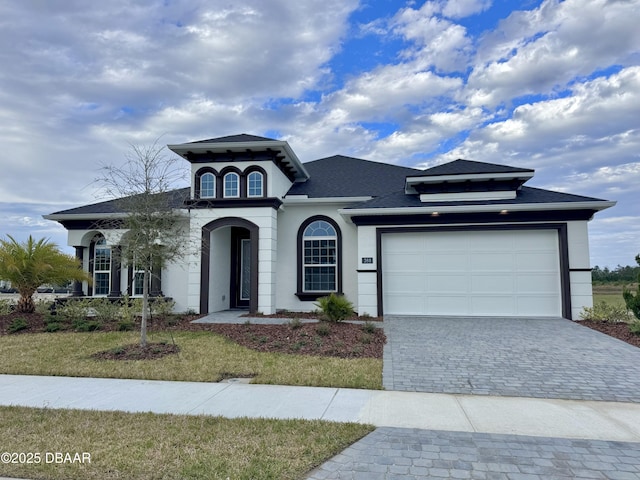 view of front of home with decorative driveway, a garage, and stucco siding