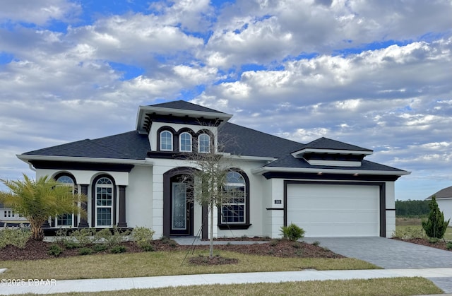 view of front of property featuring stucco siding, a shingled roof, decorative driveway, and a garage