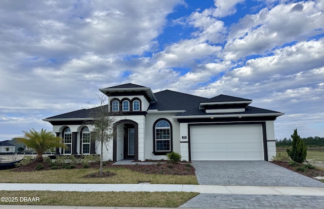 view of front of home featuring a garage, decorative driveway, and stucco siding