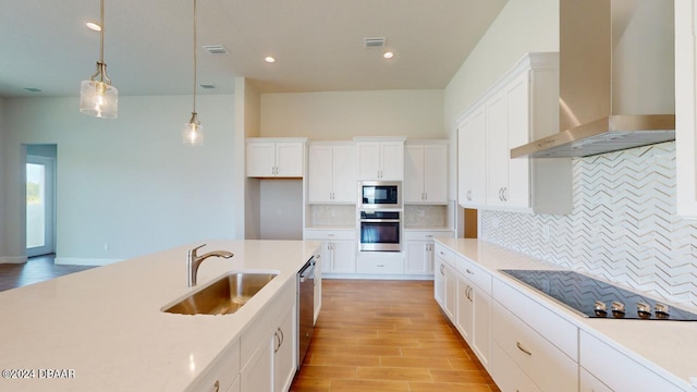 kitchen featuring a sink, wall chimney range hood, stainless steel appliances, light wood finished floors, and light countertops