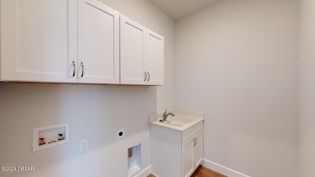 washroom featuring a sink, cabinet space, baseboards, hookup for an electric dryer, and hookup for a washing machine