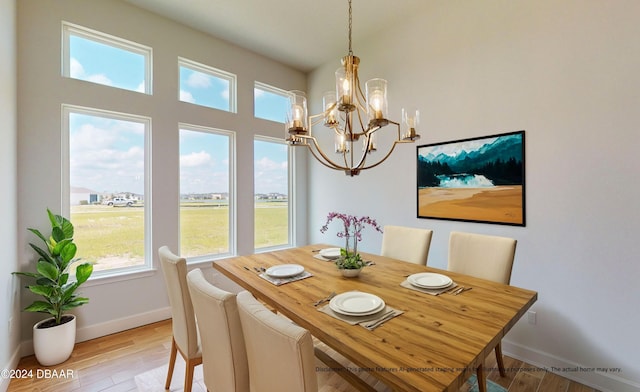 dining area featuring light wood finished floors, a notable chandelier, and baseboards