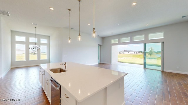 kitchen featuring visible vents, stainless steel dishwasher, open floor plan, and a sink