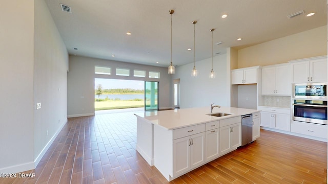 kitchen with visible vents, a sink, appliances with stainless steel finishes, light countertops, and decorative backsplash