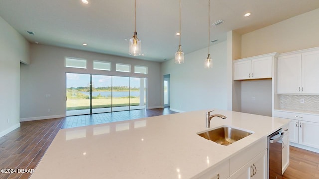 kitchen with dark wood finished floors, a sink, open floor plan, stainless steel dishwasher, and tasteful backsplash