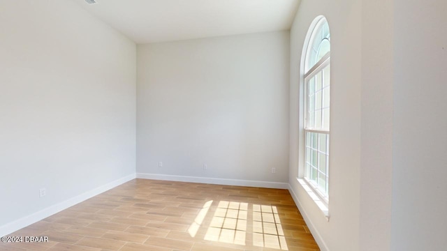 unfurnished room with a wealth of natural light, light wood finished floors, and baseboards