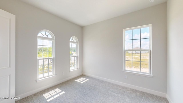 carpeted spare room featuring baseboards