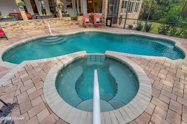 view of pool featuring a patio area, a lanai, and an in ground hot tub