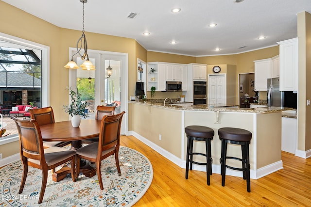 kitchen with kitchen peninsula, light hardwood / wood-style floors, white cabinets, and appliances with stainless steel finishes