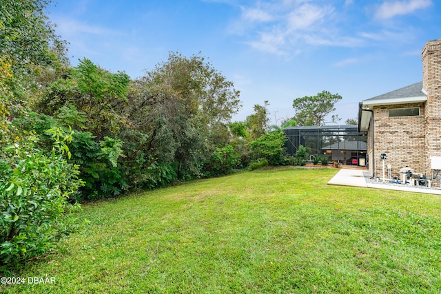 view of yard featuring glass enclosure and a patio