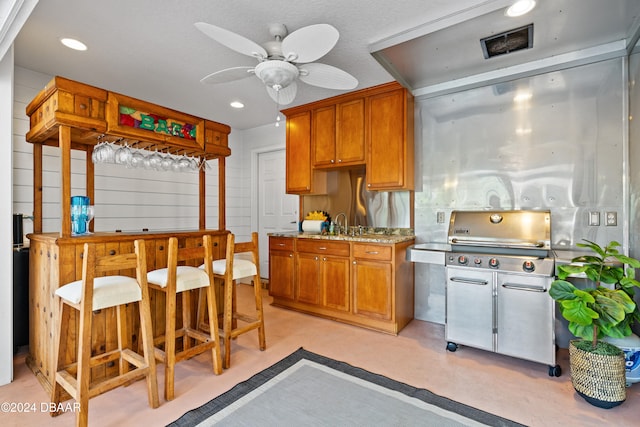 kitchen with ceiling fan and light stone counters