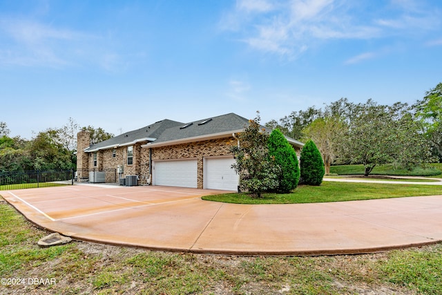 view of property exterior with a lawn, a garage, and cooling unit