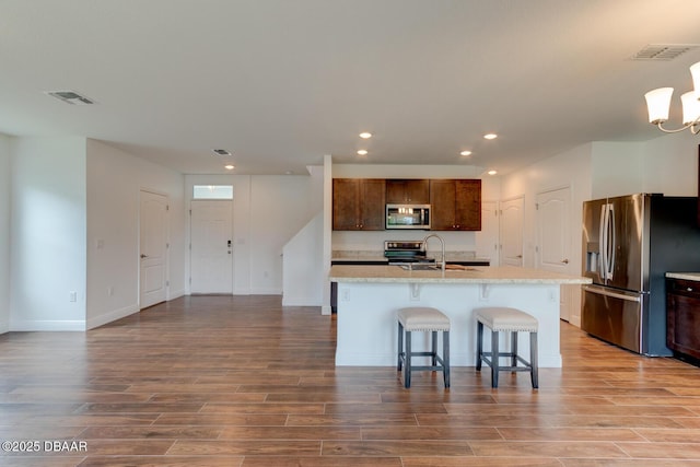 569 Armoyan Way, New Smyrna Beach, FL 32168 - kitchen featuring stainless steel appliances, a sink, wood finished floors, recessed lighting, and a kitchen bar