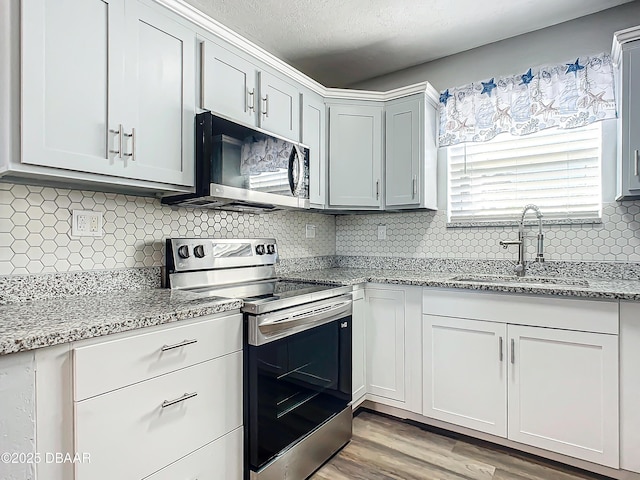 kitchen with white cabinets, sink, light wood-type flooring, and stainless steel appliances