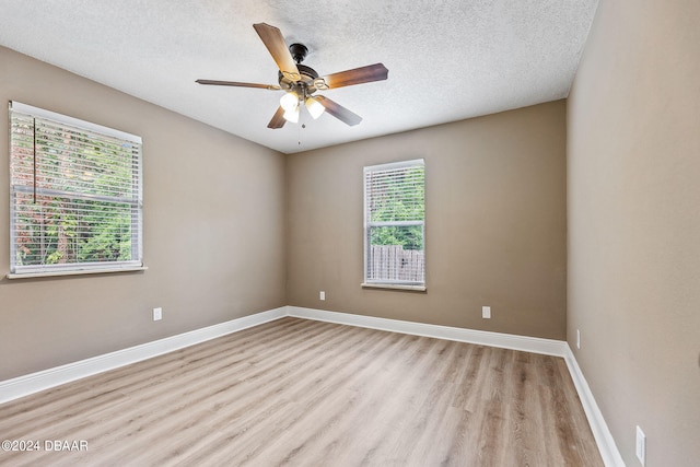 unfurnished room featuring a textured ceiling, light hardwood / wood-style floors, a healthy amount of sunlight, and ceiling fan