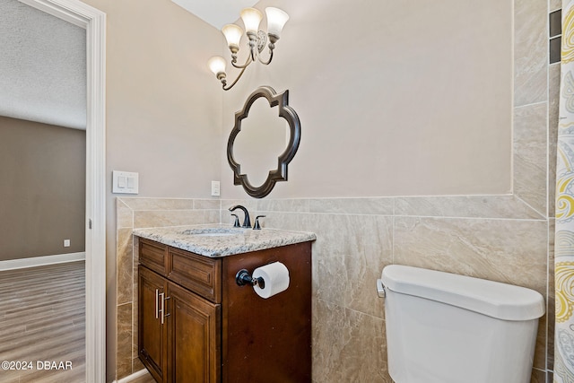 bathroom with vanity, tile walls, wood-type flooring, and a textured ceiling